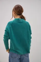 Sweater de tejido de punto en color verde, con cuello alto tipo mock neck y mangas largas con costuras raglán. Presenta un diseño de textura granulada y corte recto.