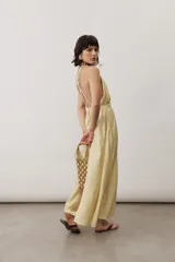 Vestido largo color amarillo con tirantes finos cruzados en la espalda, escote en V y diseño fluido con falda amplia.