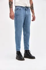 Jean de corte mom fit en color azul medio con acabado marmolado, confeccionado en denim resistente. Presenta cierre frontal con botón, bolsillos laterales y traseros, y un ajuste ligeramente holgado en las piernas con terminación recta.
