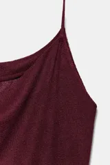 Top de punto color vino tinto con acabado brillante, escote fluido tipo *cowl neck* y tirantes finos. Presenta un detalle de cinturón fino en el mismo tejido que ajusta la parte inferior, creando un ligero peplum.