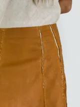 Pollera larga de lino color blanco, con corte acampanado y paneles verticales con costuras a la vista.