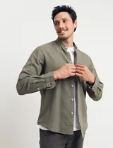 Camisa de cuello mao y manga larga, confeccionada en una mezcla de lino y algodón. Presenta un diseño de corte recto con botones en tono natural y un bolsillo pequeño en el pecho.