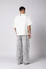 Pantalón de jean con corte baggy y fit oversize, de color gris con efecto lavado ácido. Presenta costuras reforzadas y diseño de pierna ancha.
