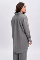 Camisa de jean de corte oversize y largo tipo túnica en color gris desgastado, con mangas largas, cuello camisero y cierre frontal de botones.