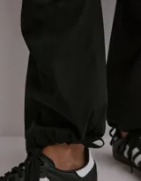 Pantalón cargo negro de popelina de algodón, con corte holgado, cintura ajustable y múltiples bolsillos laterales y traseros.