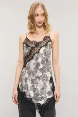 Top de satén con estampado estilo paisley en tonos blanco y negro, corte al bies, escote en V con apliques de encaje negro en el escote y el ruedo asimétrico. Cuenta con breteles regulables y tirantes finos.