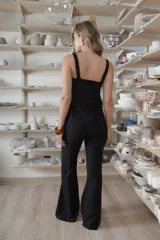 Pantalón negro de corte acampanado, con costuras visibles y laterales de encaje negro con textura.