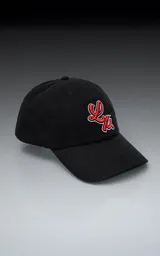 Gorra de gabardina color negro con visera curva y bordado frontal en hilo rojo con borde blanco que simula una letra 'L' estilizada. Posee ajuste trasero de velcro.
