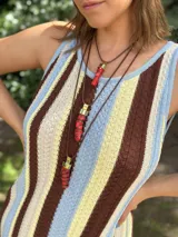 Collar con dije de coral natural engarzado en bronce dorado, con tiento sintético color camel y cierre deslizable para regular el largo.