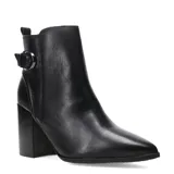 Bota corta de cuero negro con taco cuadrado y punta fina. Presenta una tira decorativa con hebilla metálica en el lateral externo y cierre en el lateral interno.