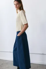 Jeans de tiro medio con diseño culotte y pierna ancha. Presenta cinco bolsillos, detalle de pinzas en el delantero y cierre frontal con cremallera y botón metálico.