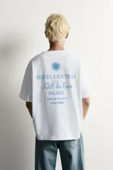 Remera blanca de corte relaxed fit con cuello redondo y manga corta. Presenta un estampado frontal en color celeste con el texto "HOTEL CENTRAL" acompañado de cinco estrellas.
