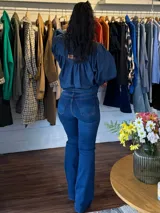 Jean de tiro alto en denim azul, con corte ajustado en la parte superior y botamanga ligeramente acampanada.