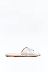 Sandalia baja plateada con capellada trenzada tipo cordón, de textura artesanal y diseño envolvente. La suela presenta un delicado bordado a tono, que realza el acabado y suma un detalle distintivo al modelo.