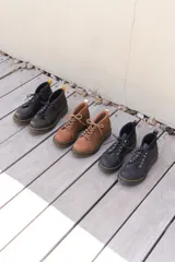 Borcego negro de cuero con cordones, suela track y detalle de costuras amarillas.