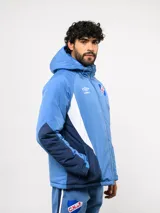 Campera de abrigo Umbro del Club Nacional de Football, con diseño de bloques de color en azul, blanco y rojo. Cuenta con capucha ajustable, cierre frontal y logo de la marca junto al escudo del club en el pecho.
