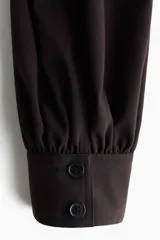 Pantalón negro de corte holgado con diseño de piernas globo, pinzas en la cintura y puños ceñidos en los tobillos.