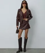 Campera de mujer confeccionada en material sintético tipo PU, con diseño de cuello solapa, hombreras estructuradas y cierre frontal asimétrico con cremallera. Presenta un corte regular y mangas largas.