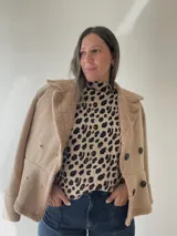 Chaqueta negra con forro tipo corderito, doble botonadura y cuello solapa.