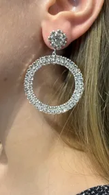 Aros colgantes compuestos por un aplique superior en forma de flor con strass y una argolla circular grande totalmente recubierta de cristales brillantes.