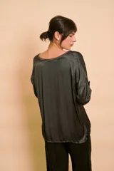 Blusa holgada de satén color beige, con escote en V y mangas largas con trabilla para sujetar remangadas.