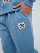 Pantalón jogger celeste de felpa, con cintura elástica ajustable con cordón, puños elastizados en los tobillos y un parche con el logo de la marca en la pierna izquierda.