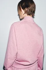 Sudadera de algodón color rosado con cuello alto, cierre frontal con cremallera metálica y manga larga. Presenta aplicación metálica en el pecho y acabados en rib.