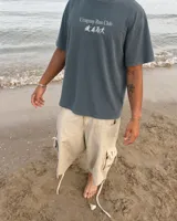 Remera marrón oversize con cuello redondo y mangas cortas. Estampado frontal con el texto "Uruguay Run Club" en celeste y siluetas blancas de personas corriendo.