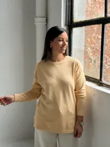 Sweater de punto color manteca con diseño de rombos en relieve, cuello redondo y mangas largas con puños ajustados.