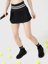 Falda tipo skort de color negro con diseño plisado y cintura alta elástica con detalles de líneas blancas. Incluye short integrado con bolsillo lateral.