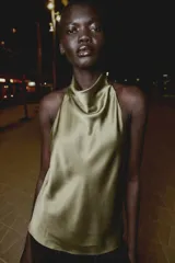 Top de cuello halter con espalda descubierta, confeccionado en tejido satinado con caída fluida y cierre trasero con botones ocultos.