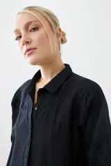 Túnica negra con bordados y bolsillos laterales.