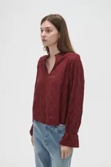 Blusa de viscosa color bordó con diseño bordado geométrico, cuello en V y mangas largas con terminación en volados.
