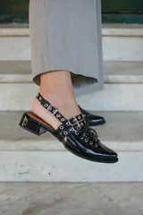 Sueco de cuero color borgoña con cordones, ojales y hebillas plateadas. Tiene tira trasera regulable con elástico.