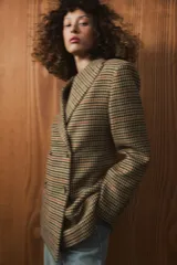 Blazer de corte entallado con estampado de cuadros, cuello solapa y cierre frontal cruzado con botones. Presenta mangas largas con detalle de abertura y botones en los puños, y forro interior a contraste.