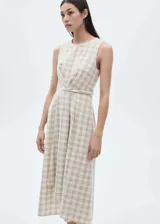 Vestido midi sin mangas con cuello redondo, confeccionado en algodón con estampado de cuadros. Presenta un diseño evasé con detalle de nudo en la cintura y cierre posterior.