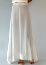 Conjunto de top y falda larga color blanco. El top es musculosa con volados en el ruedo y la falda es larga y recta.