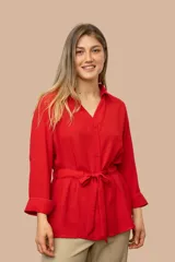 Camisa de seda color celeste, con cuello camisero, mangas largas y lazo ajustable en la cintura que genera un efecto fruncido.
