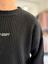 Sweater de punto color marrón, de manga larga, con textura acanalada y texto bordado en la espalda.