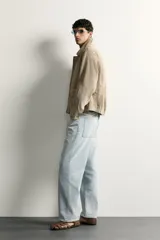Cazadora relaxed fit de piel y ante color beige, con cuello solapa, manga larga con puño, bolsillos delanteros con solapa y cierre frontal oculto con cremallera y botones a presión.