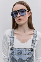 Jumper de jean corto, de color celeste claro con estampado floral en tonos oscuros. Presenta tirantes regulables con hebillas metálicas, bolsillo pectoral y bolsillos laterales funcionales.