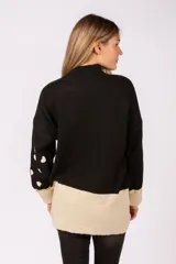 Sweater de punto negro con estampado de corazones blancos, cuello alto y puños en color beige. Presenta un diseño con tajos laterales y ruedo en contraste de color beige.