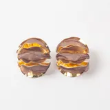 Caravanas circulares de diseño estructurado, compuestas por capas alternas de metal dorado y tela roja plisada.