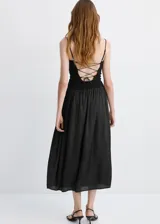 Vestido midi color negro con cuerpo ajustado de escote redondo y tirantes finos, combinado con una falda larga fruncida de tejido ligero y fluido.