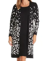 Vestido midi de tejido de punto con diseño integrado que simula un conjunto de vestido y cárdigan. Presenta un color base negro con detalles geométricos en blanco en las mangas y el ruedo. Posee escote redondo y mangas largas.