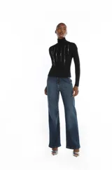 Blusa de cuello alto y manga larga en color negro, confeccionada en tejido de punto suave. Presenta detalles bordados verticales en el frente con aplicaciones brillantes.