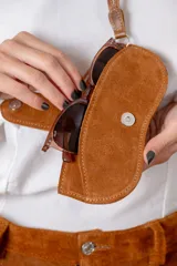 Cuelga lentes de cuero vacuno con diseño de pelo vacuno estampado tipo animal print. Cuenta con cierre de broche metálico y correa larga para colgar.