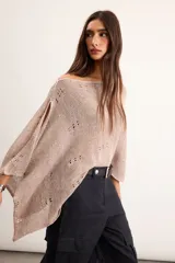 Poncho de lino tejido color tostado, con diseño asimétrico de punto abierto y mangas amplias.