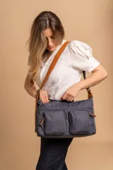 Bandolera de tafeta impermeable color beige, con dos bolsillos frontales con cierre y correa regulable. Diseño práctico y liviano ideal para uso diario.