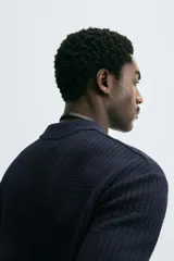 Polo de manga corta color marrón oscuro, confeccionado en tejido waffle de algodón, con cuello solapa y abertura frontal.